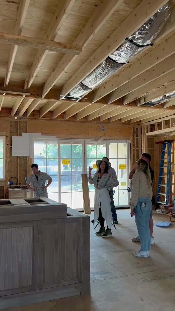 A kitchen island set among bare framing and open ceiling joists.